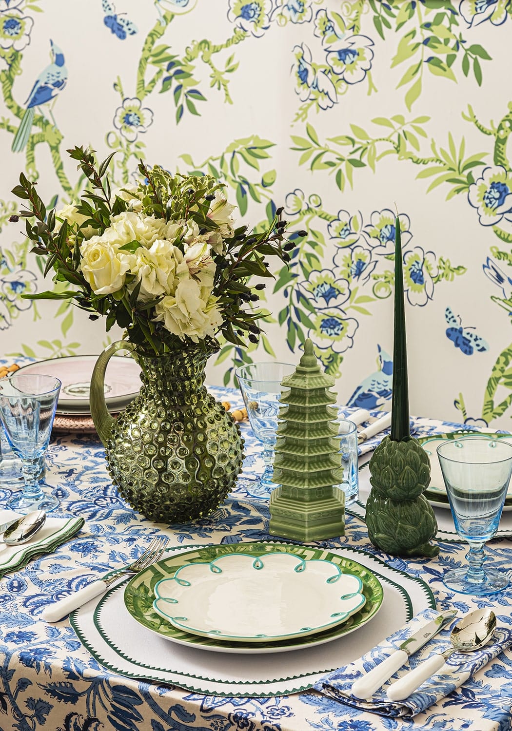 Decorative table setting with floral wallpaper featuring birds and flowers.