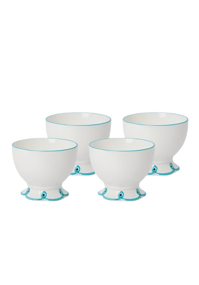Set of four white bowls with blue scalloped bases on a white background