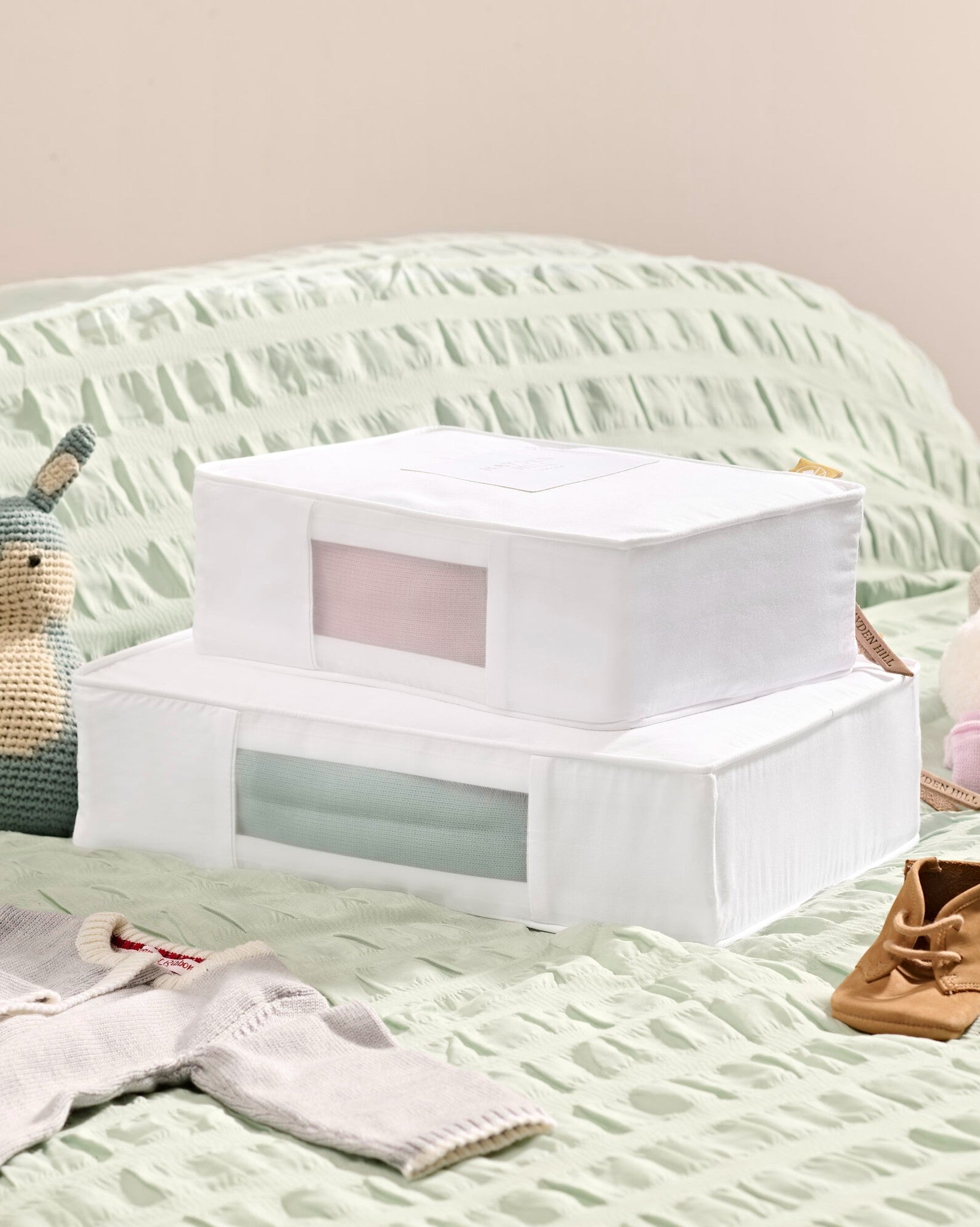 White storage box on a bed with a light green blanket