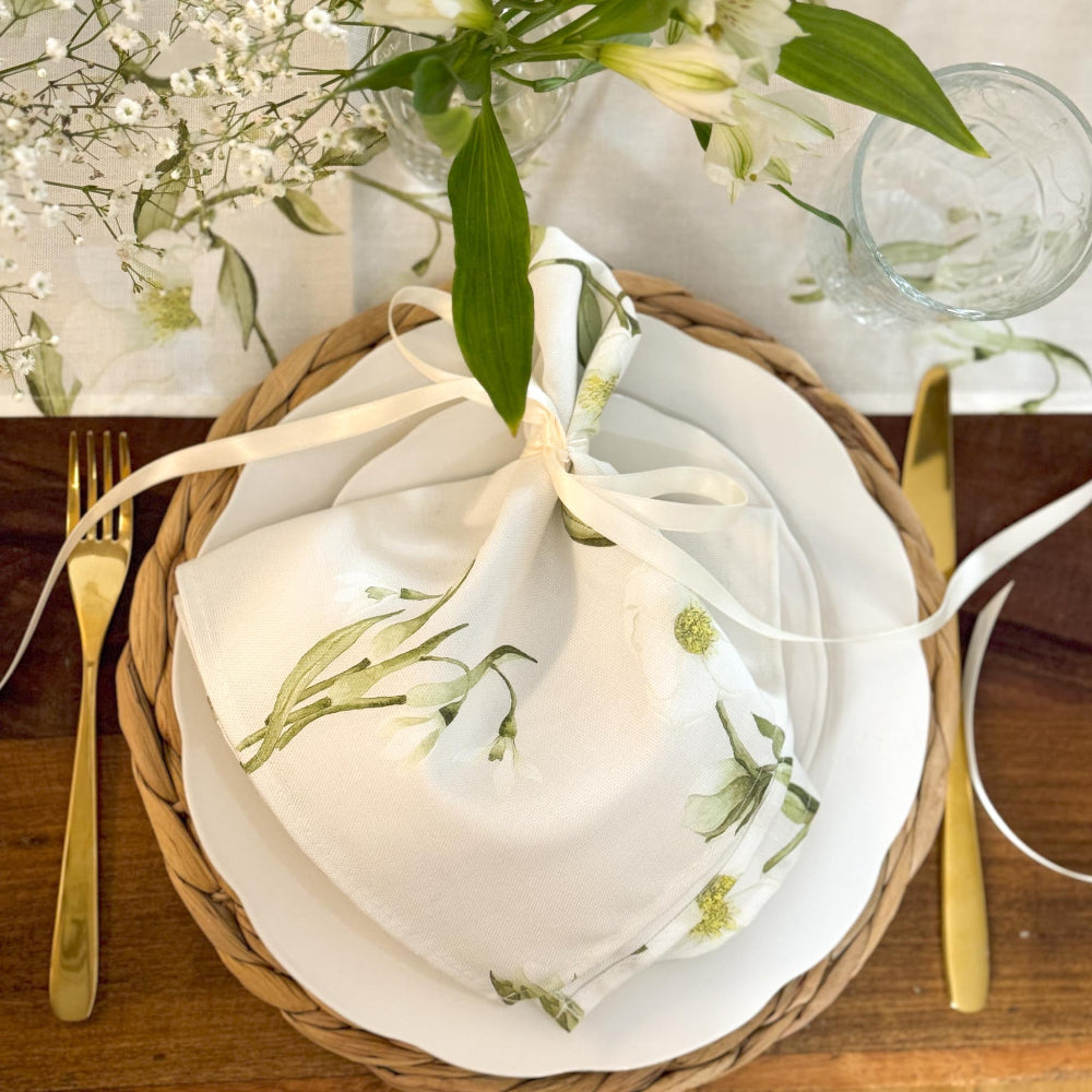 Set table with white plates, gold cutlery, and floral decorations on a wooden surface.