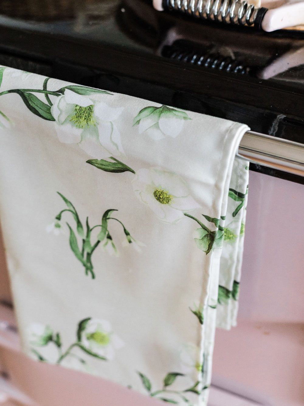Floral-patterned tea towel draped over a kitchen aga