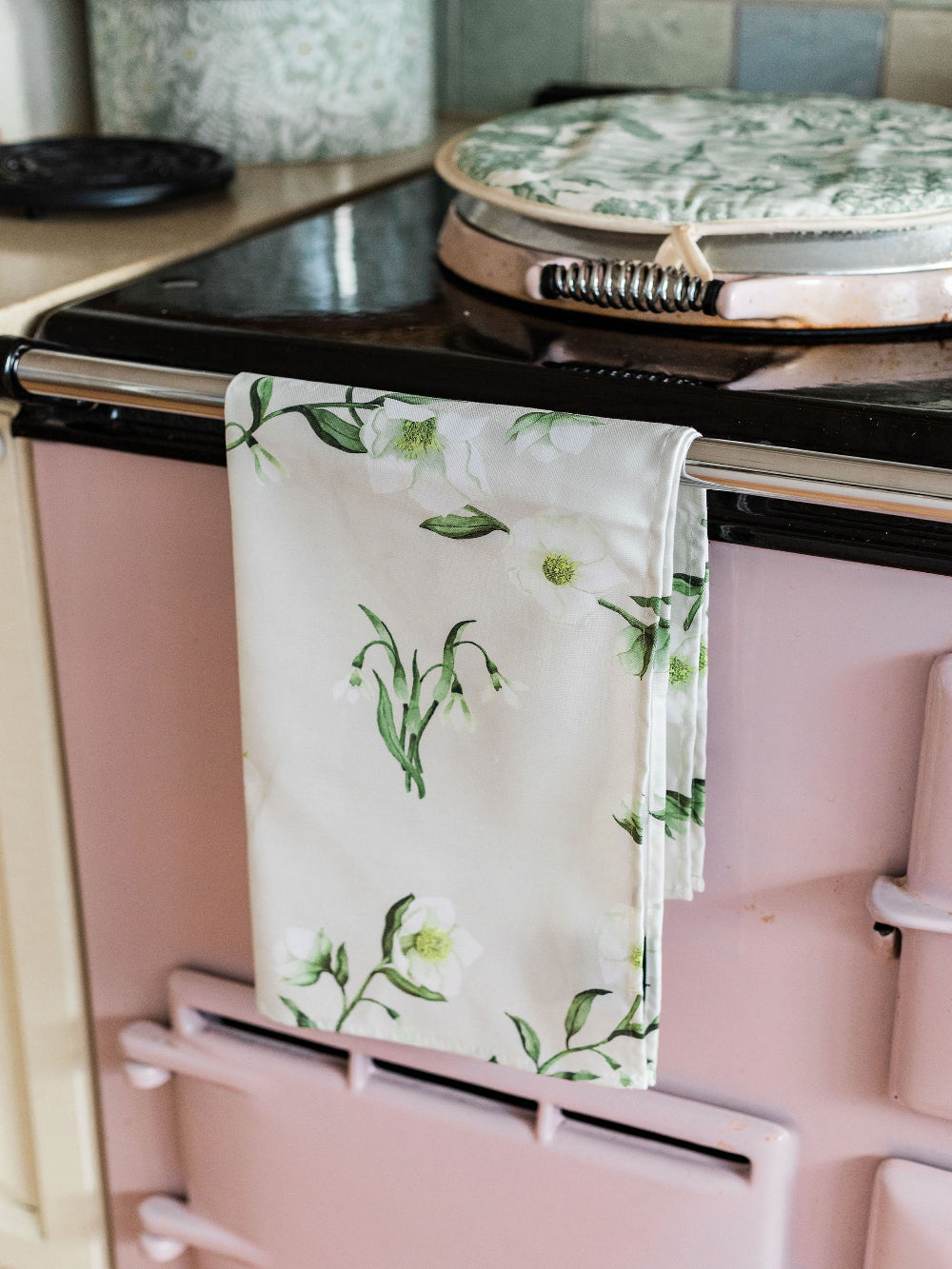 Floral-patterned towel hanging on a pink Aga range cooker.
