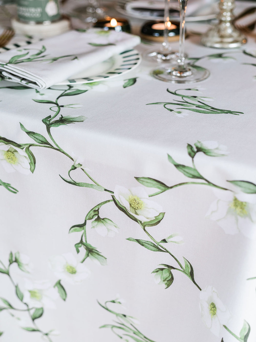 Floral patterned tablecloth on a table with cutlery and glasses.