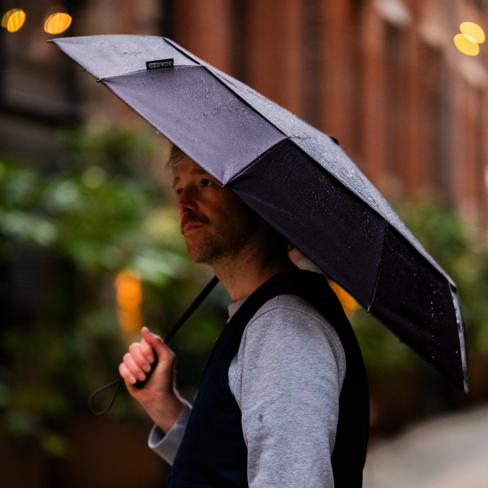 Person holding a black umbrella in an urban setting