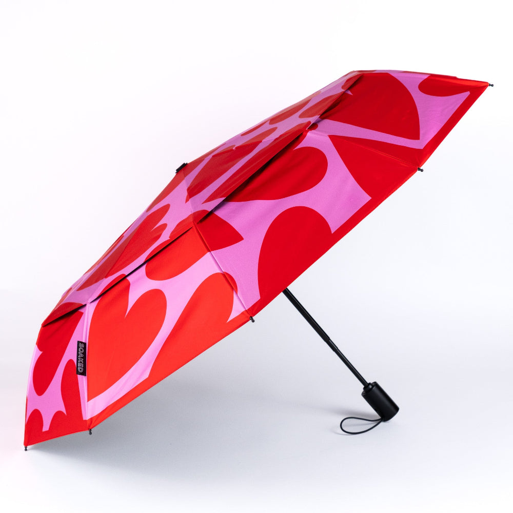 Red and pink heart-patterned umbrella on a white background