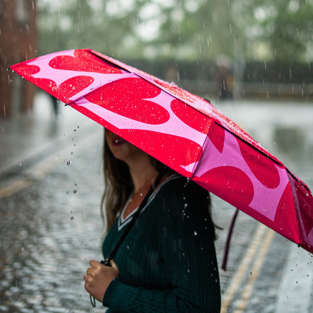 Person holding a red and pink patterned umbrella in the rain