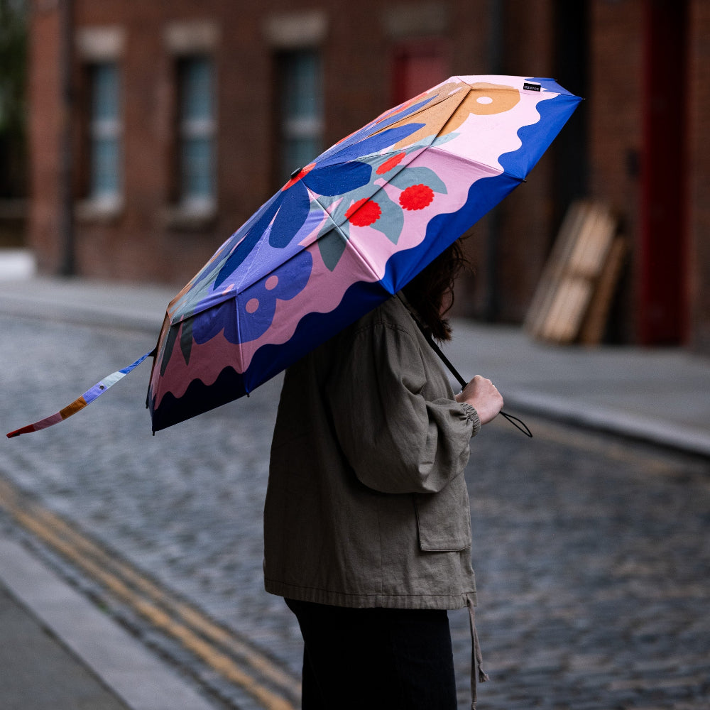Person holding a colourful umbrella on a street