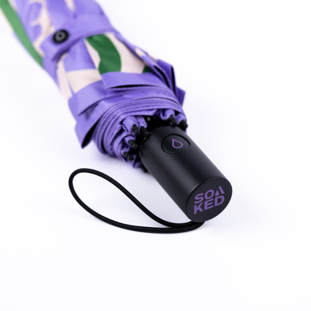 Purple umbrella with a black handle and visible brand logo on a white background