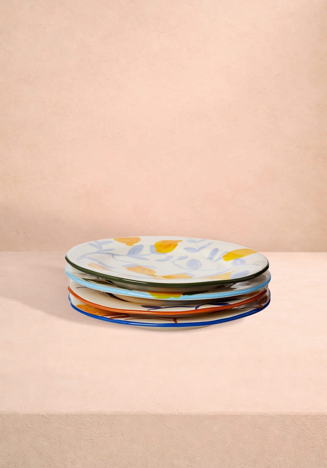 Stack of colourful ceramic plates on a beige background