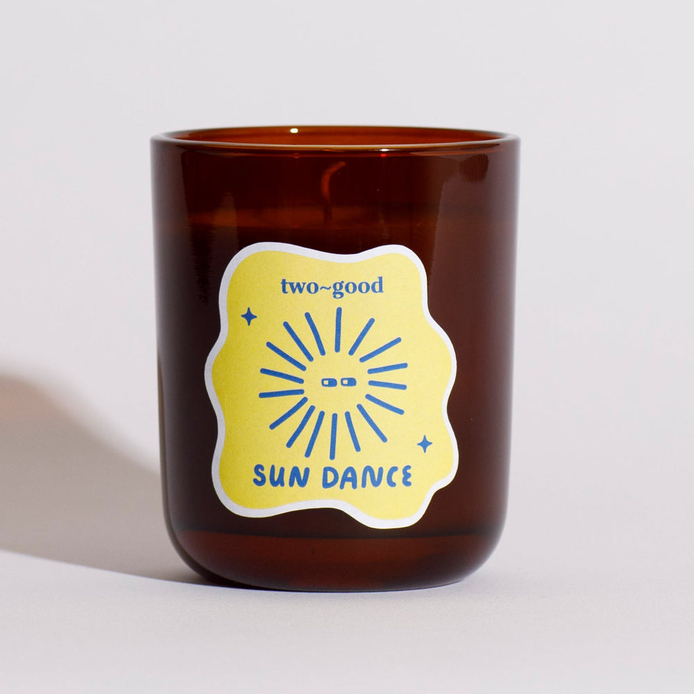 Brown glass mug with a yellow label featuring 'two-good' and 'Sun Dance' text on a light grey background.