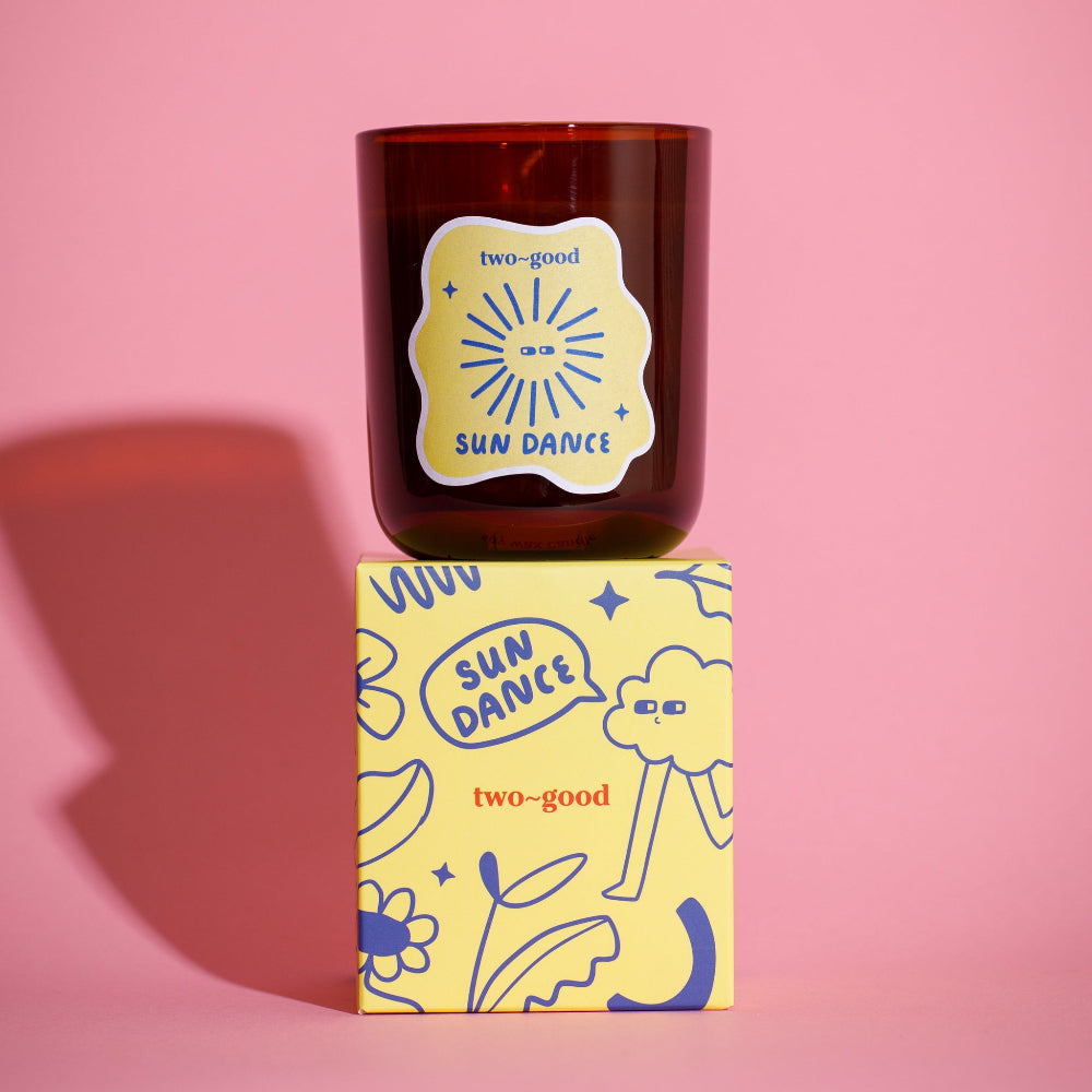 Brown candle with 'two-good' branding on a pink background