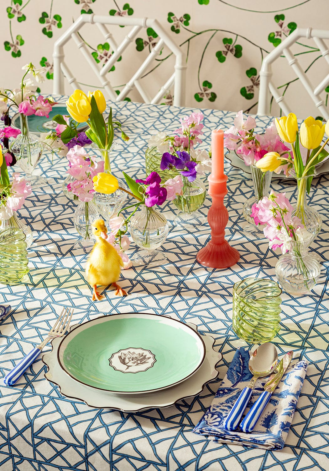 Decorative table setting with flowers, plates, and cutlery on a patterned tablecloth.