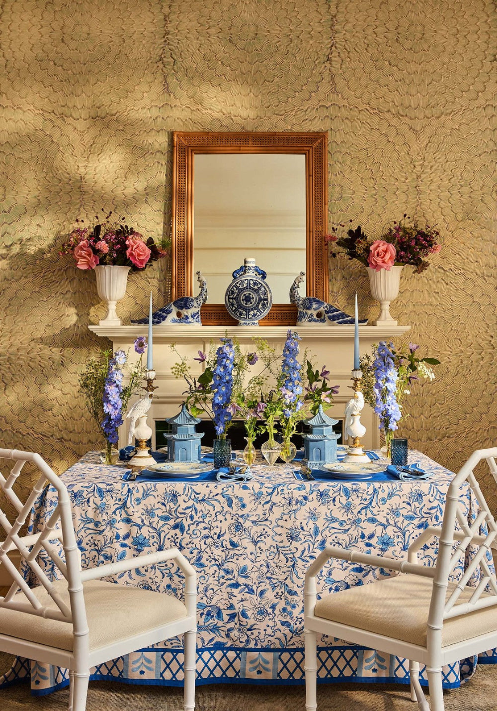 Decorative table setting with floral arrangements and a mirror on a textured wall.