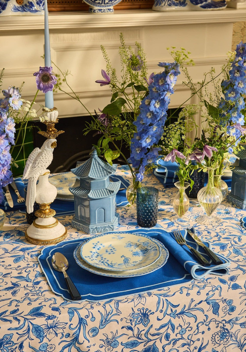 Decorative table setting with blue and white elements, including plates, vases, and a candlestick.
