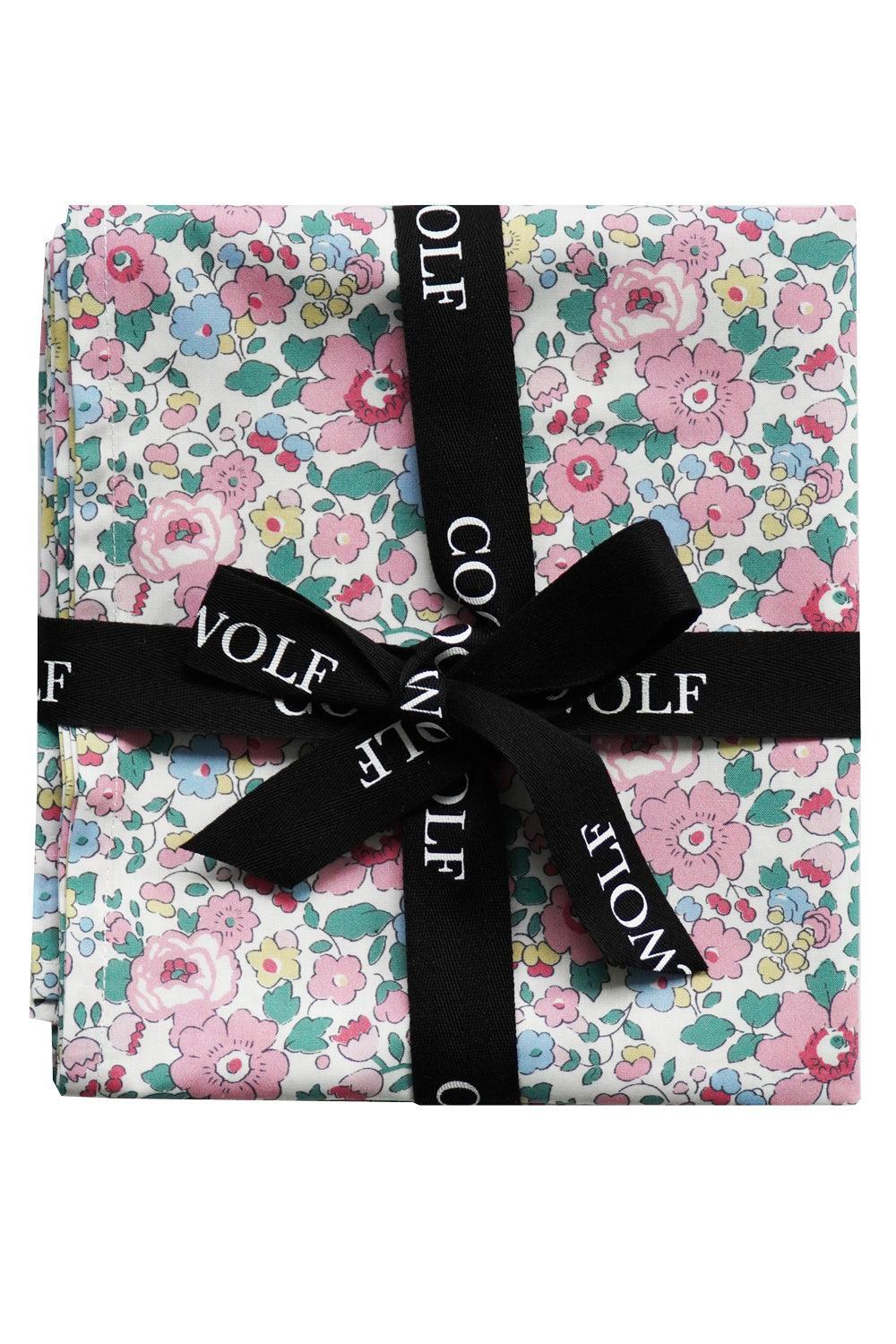 Floral-patterned fabric with a black ribbon and 'Coco + Wolf' branding on a white background