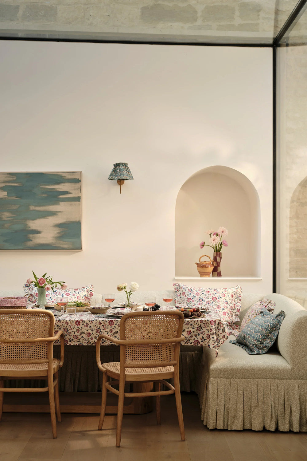 Dining area with floral tablecloth, chairs, and a sofa with decorative pillows.
