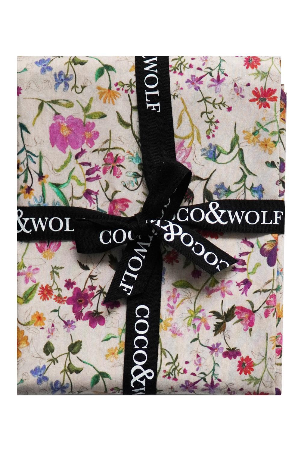 Floral-patterned Linen Garden Table runner Liberty Fabric wrapped with a black ribbon featuring 'Coco & Wolf' branding.