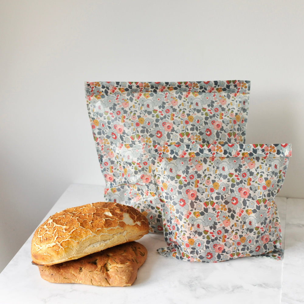 Floral-patterned liberty pattern besty reusable beeswax bags with bread on a white surface