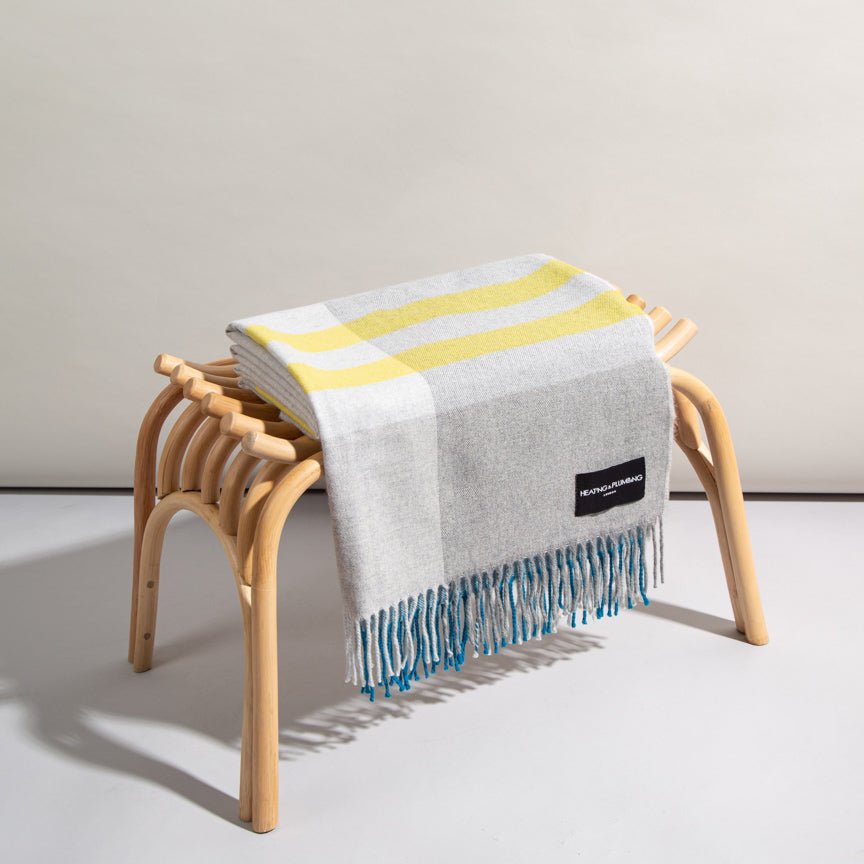 Striped blanket draped over a wooden stool on a plain background