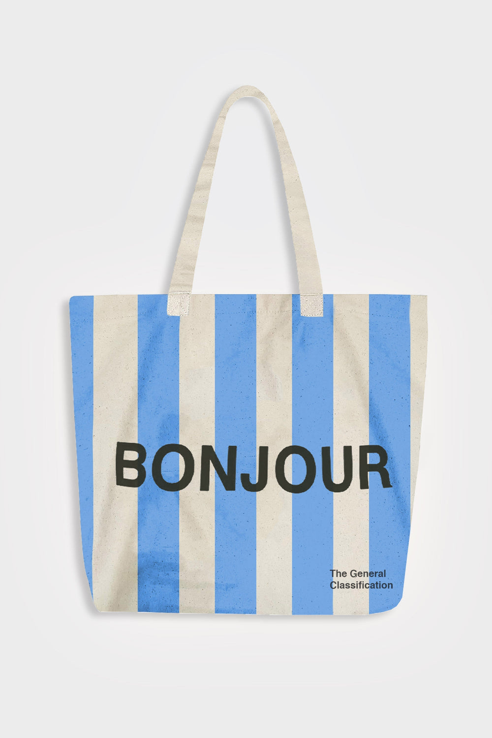 A canvas tote bag with vertical light blue and cream stripes, featuring the word 'BONJOUR' printed in bold black letters across the center and 'The General Classification' in smaller text at the bottom right. The bag has two cream fabric handles and is photographed against a light gray background.