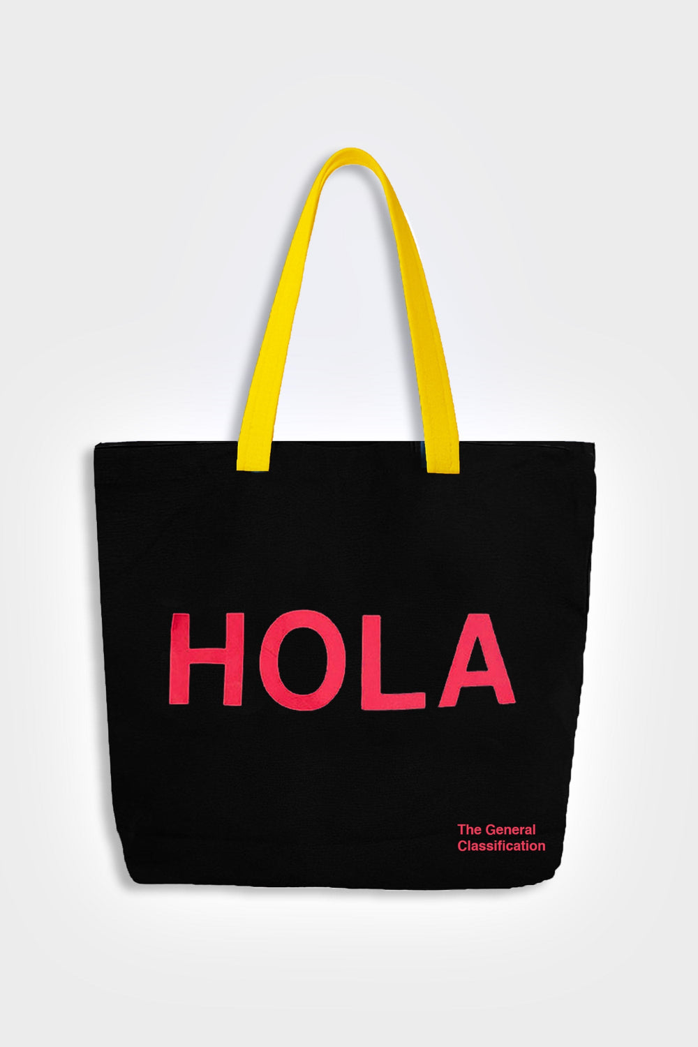 Black tote bag with 'HOLA' in pink and yellow handles on a light gray background