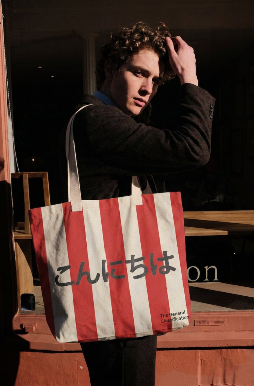 Person holding a red and white striped tote bag with japanese text