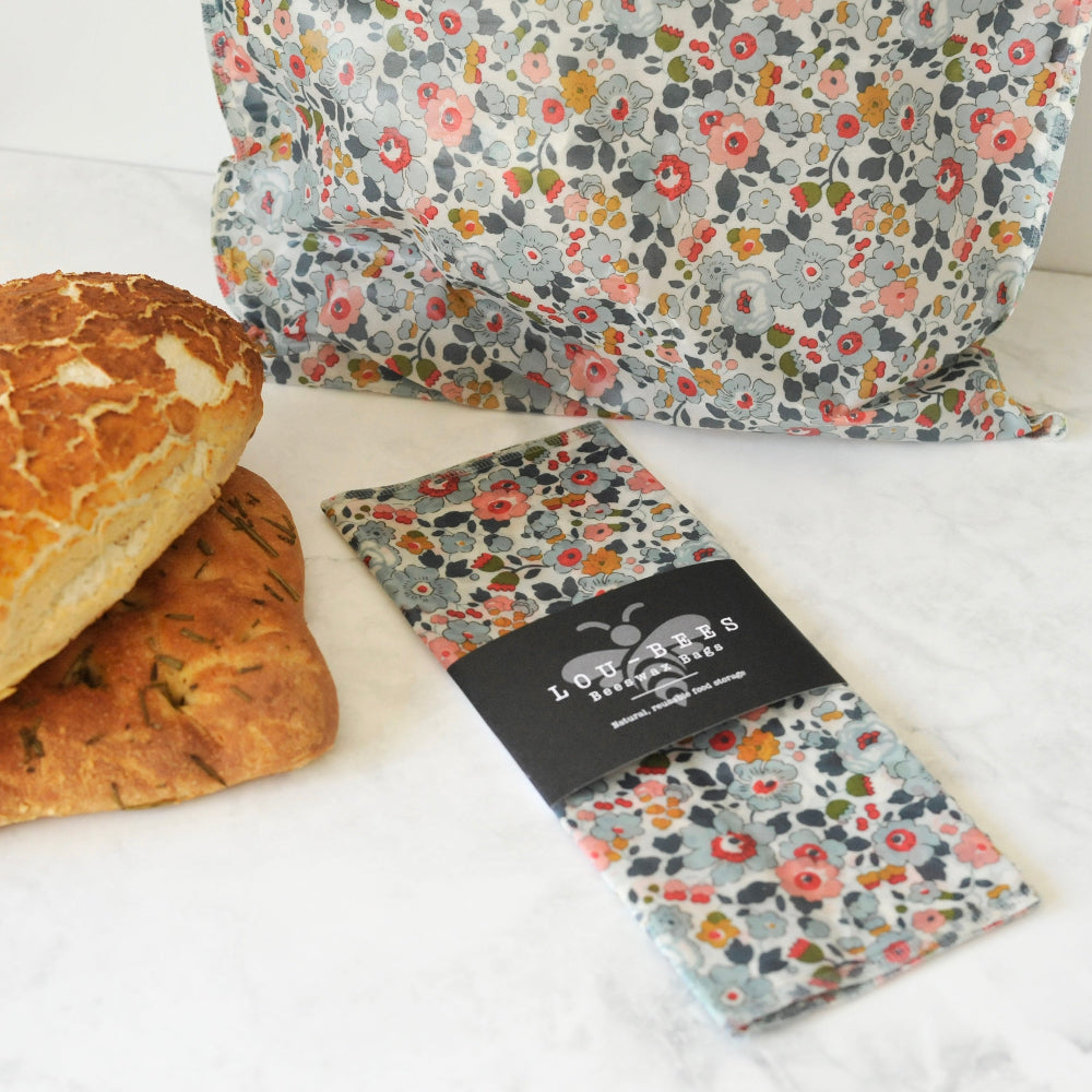 Floral-patterned beeswax bags with lou bees packaging with a loaf of bread on a white surface