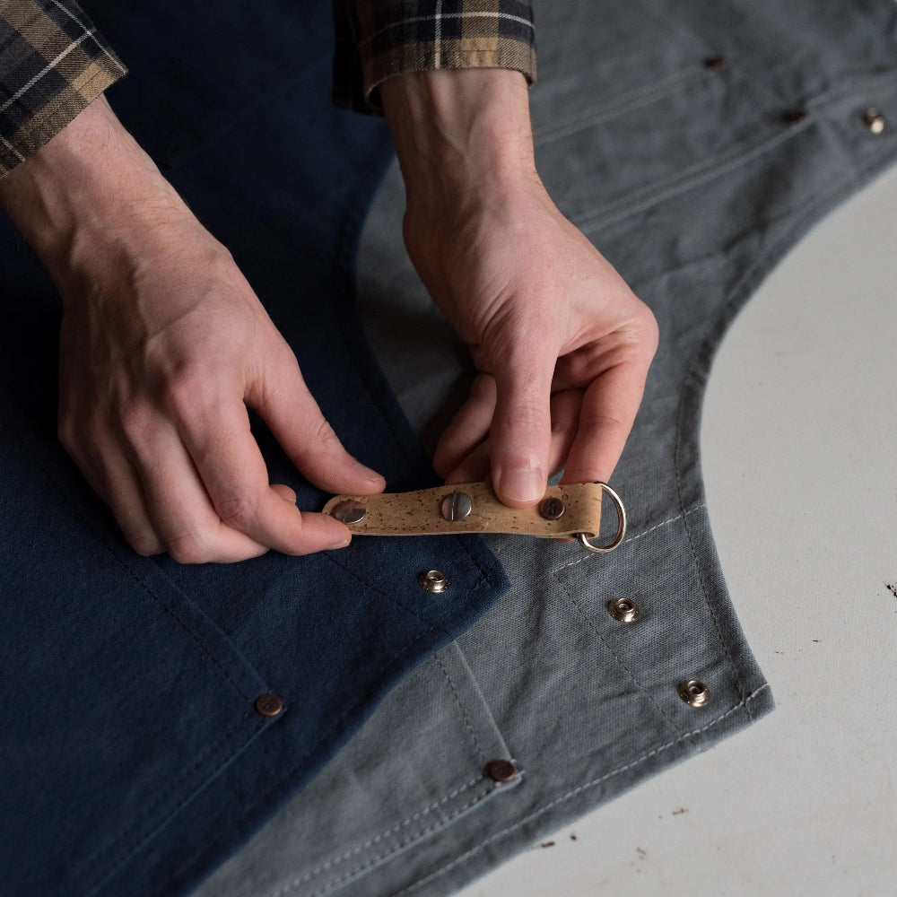 Person adjusting a cork strap on a denim apron