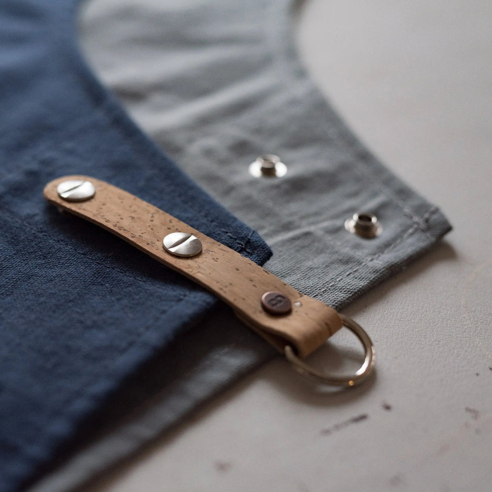 Brown cork strap with metal studs and ring on a textured surface