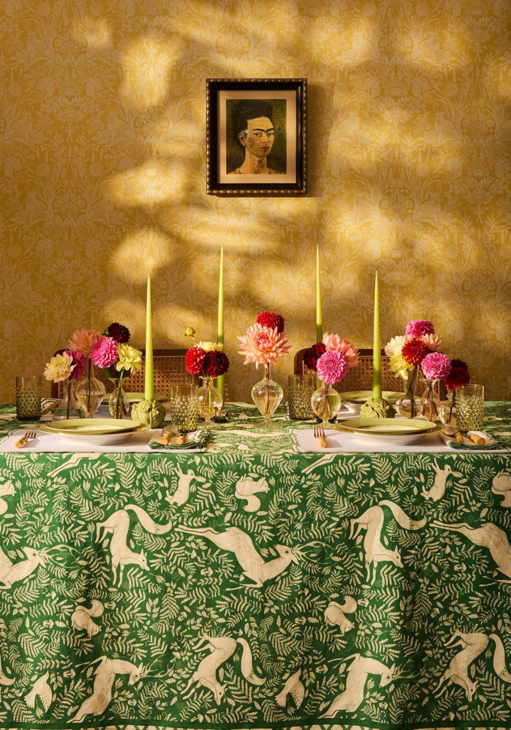 Decorative table setting with a green tablecloth featuring animal prints, candles, and flowers.