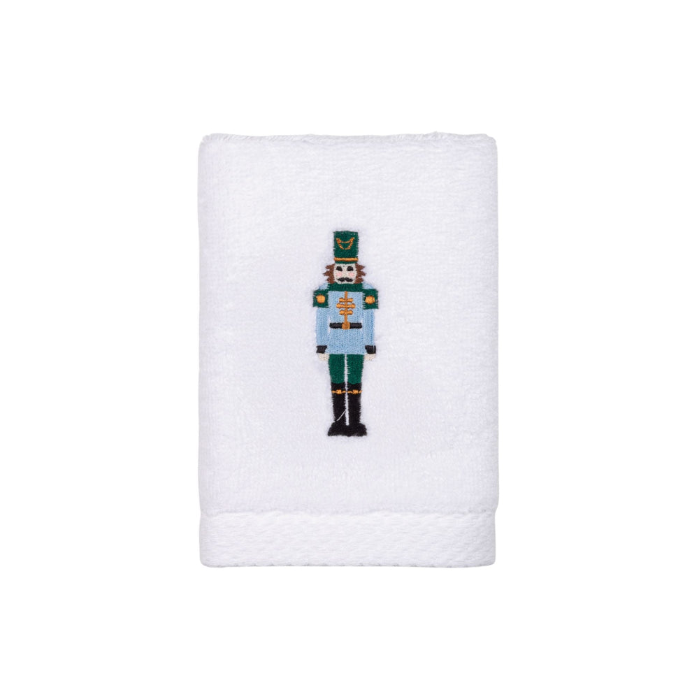White towel with a embroidered green and blue nutcracker design on a white background