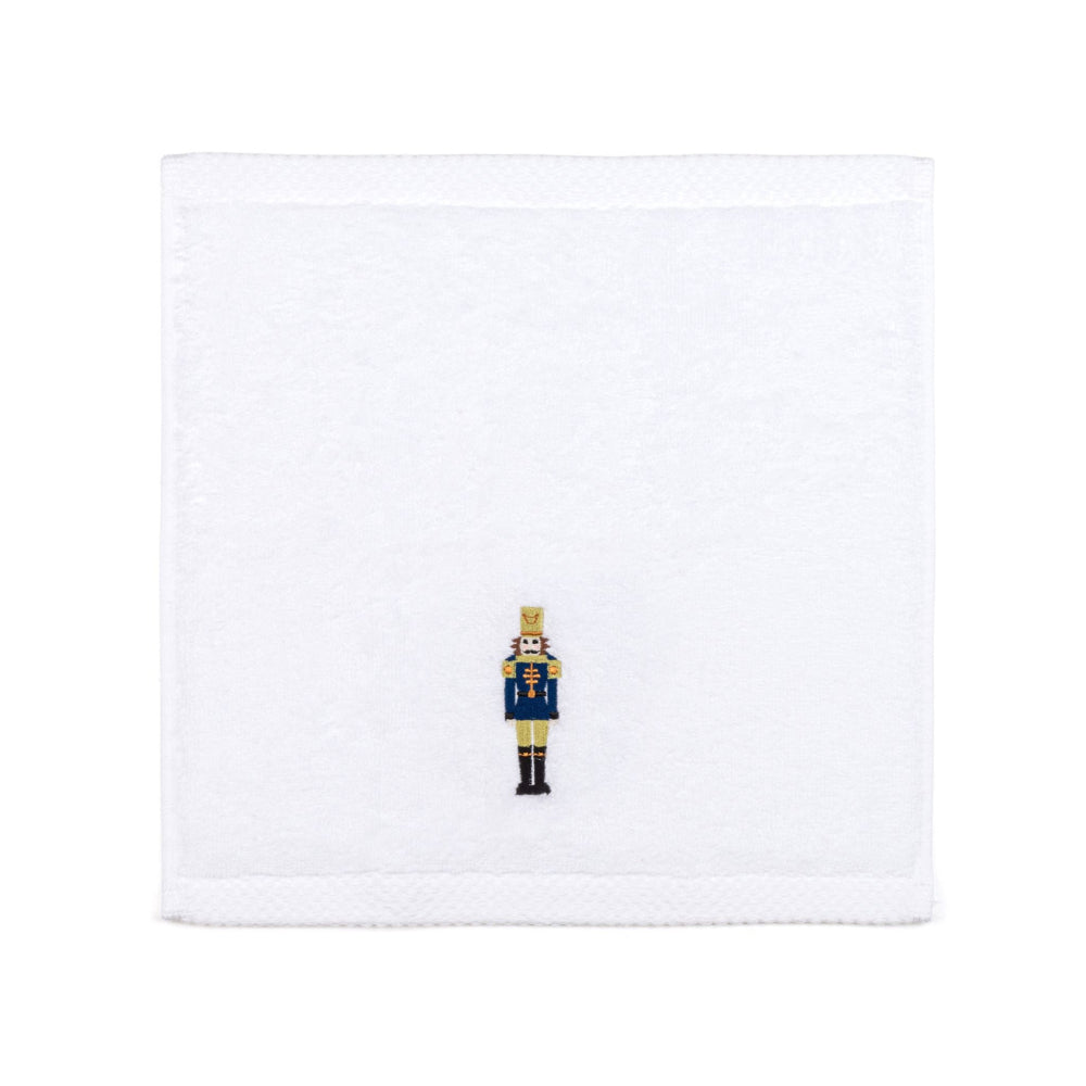 White face towel with a embroidered blue and gold nutcracker design on a white background