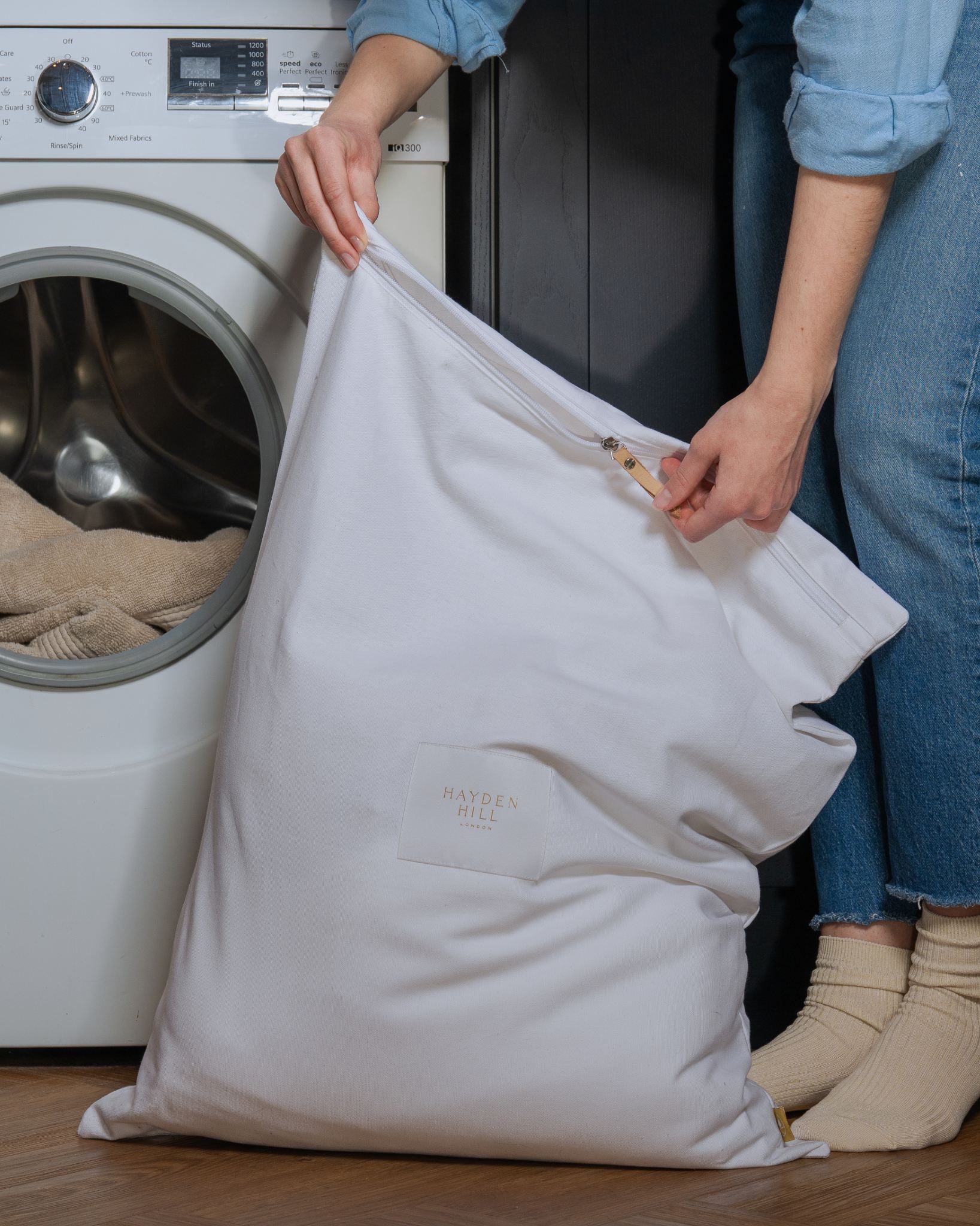 Person holding a laundry bag in front of a washing machine