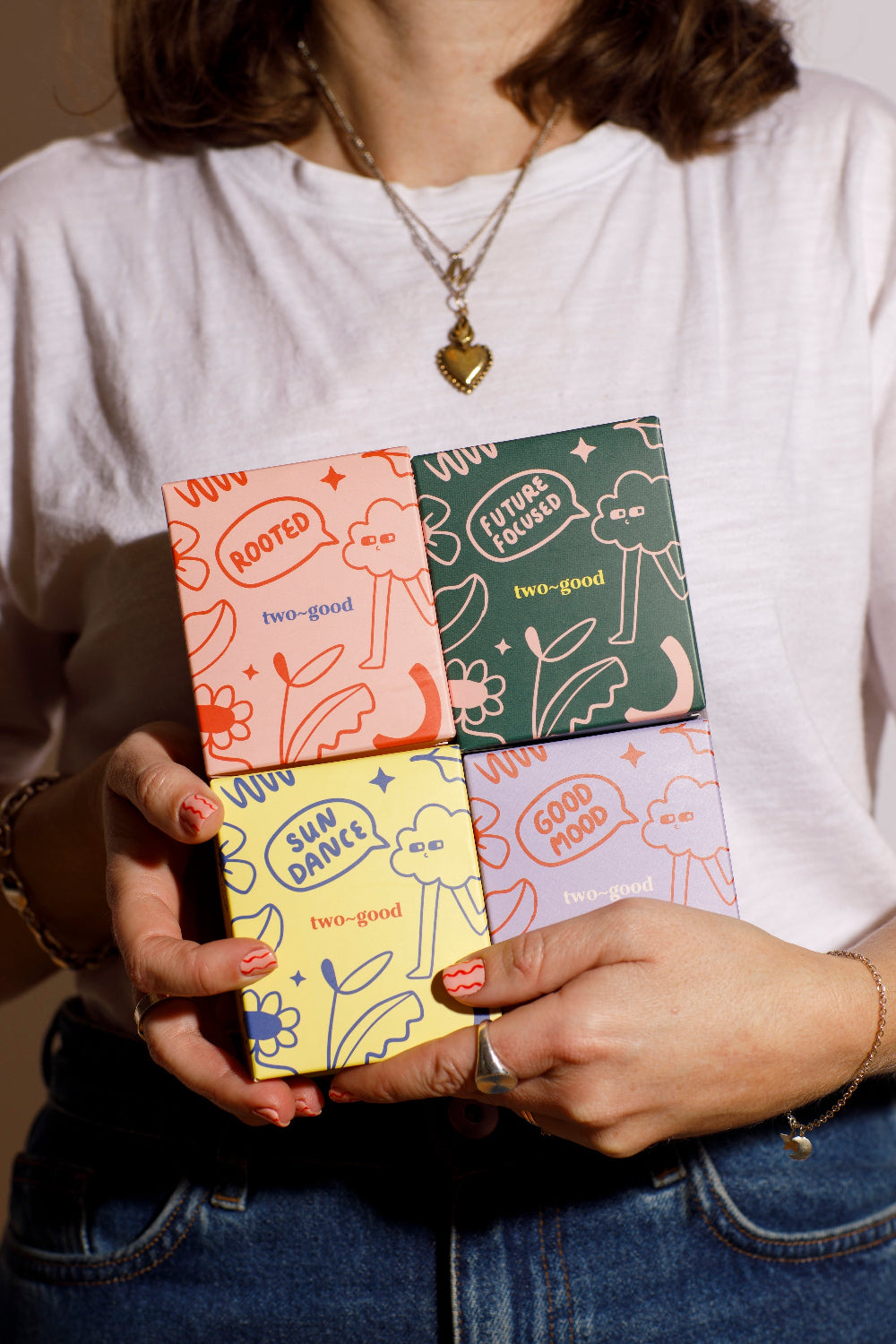 Person holding a colourful candle collection packaging with various designs on the cover