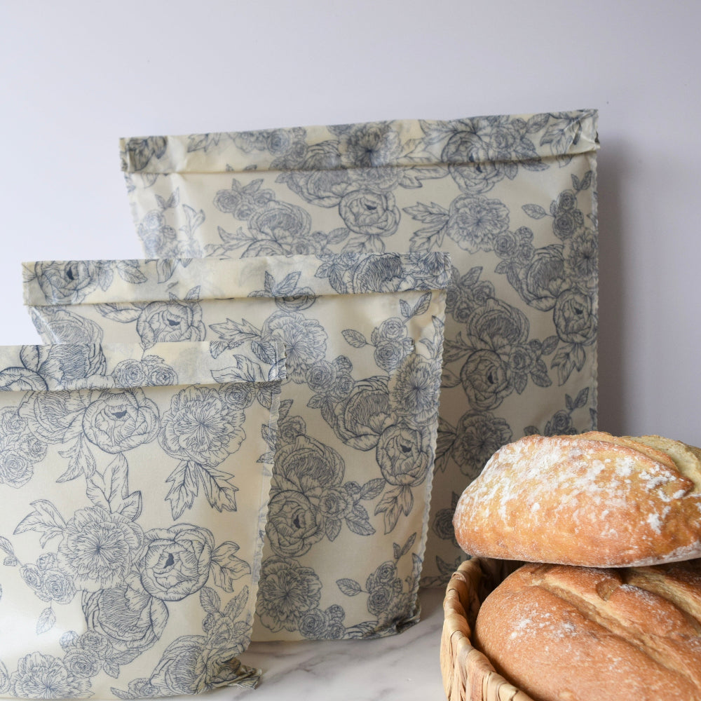 Floral-patterned beeswax bags with bread in a basket on a light background