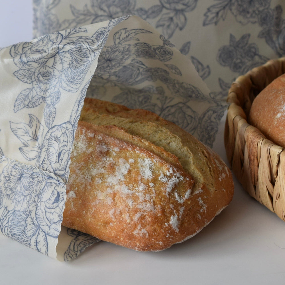 Loaf of bread with a floral-patterned beeswax bag and basket in the background