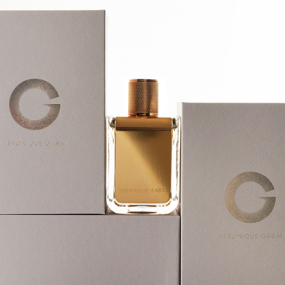 Gold perfume veronique gabai bottle with matching box on a light grey background