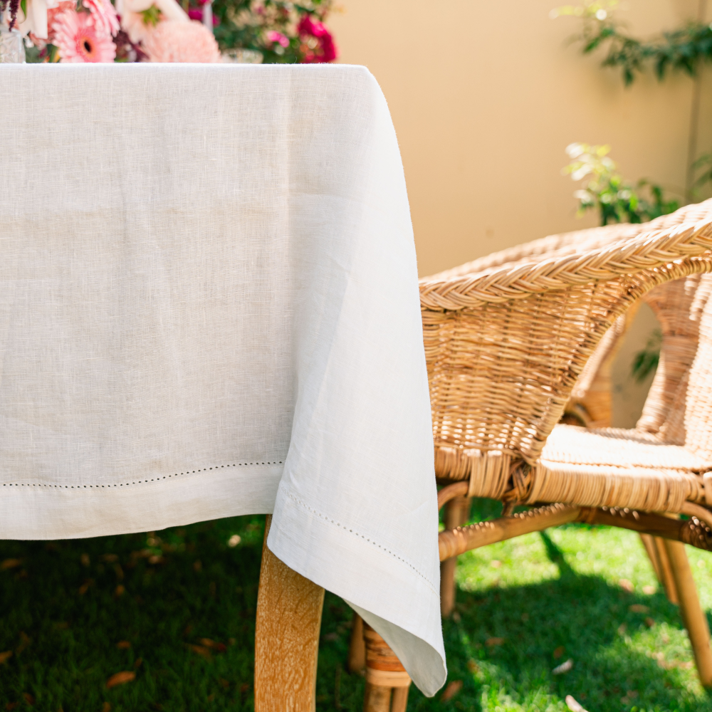 White tablecloth draped over a wicker chair outdoors with greenery in the background