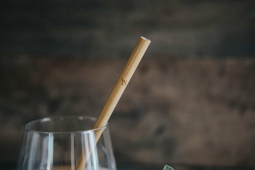 Clear glass with a bamboo straw against a blurred background