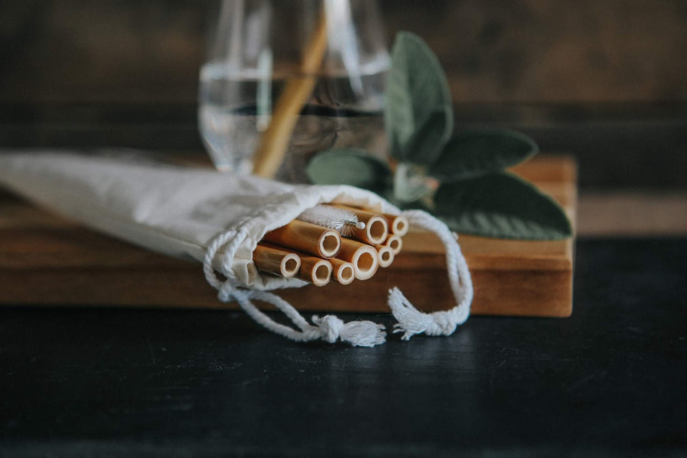 Bamboo straws in a cloth bag on a wooden block with a blurred background
