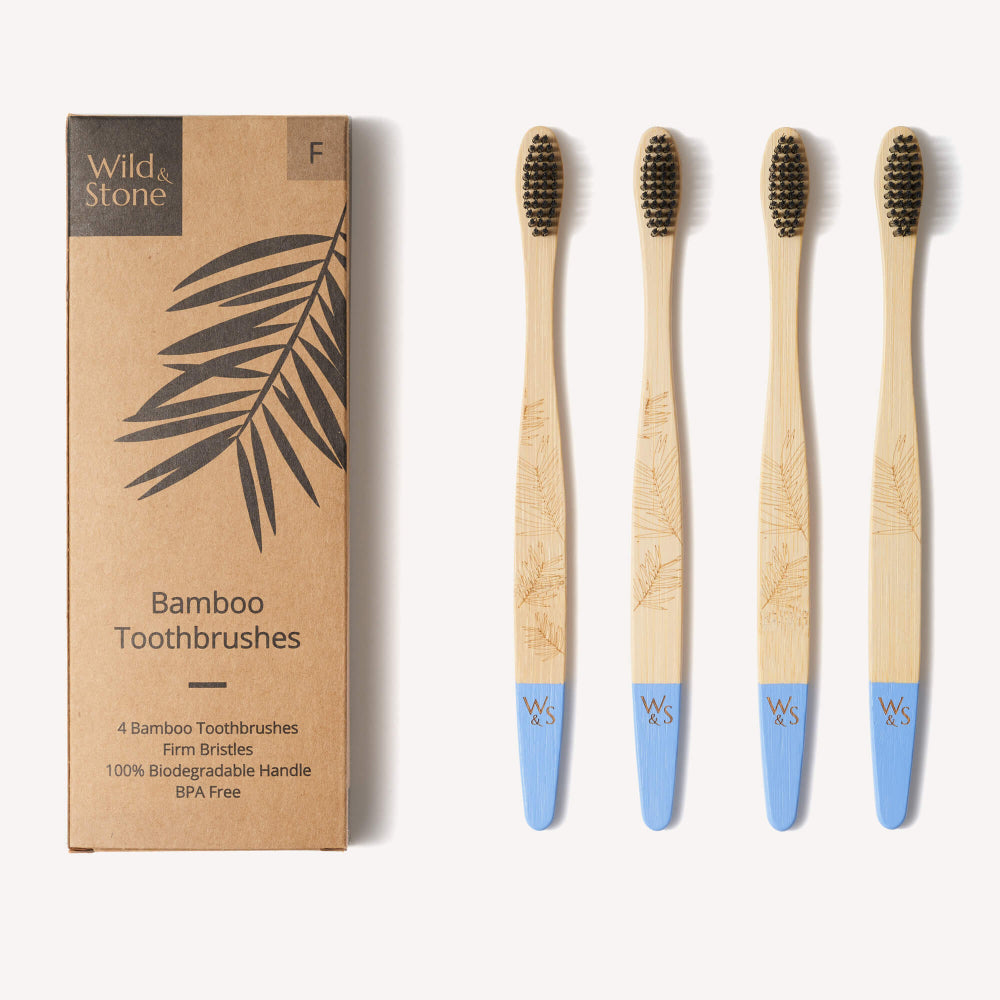 Set of four bamboo toothbrushes with blue handles next to their packaging box on a white background