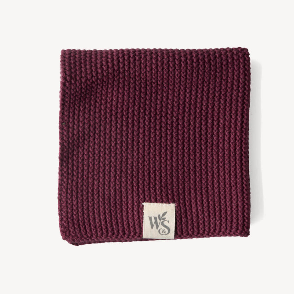 Burgandy Knitted organic dishcloth with a logo tag on a white background