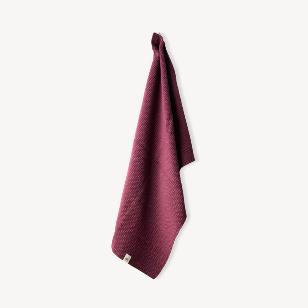 Burgandy Organic hand towel hanging on a white background