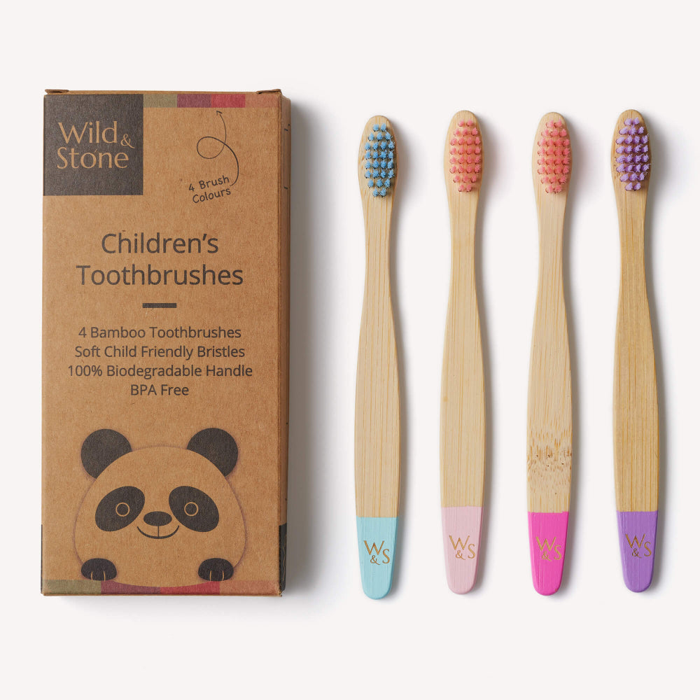Set of four children's bamboo toothbrushes with coloured bristles next to their packaging.