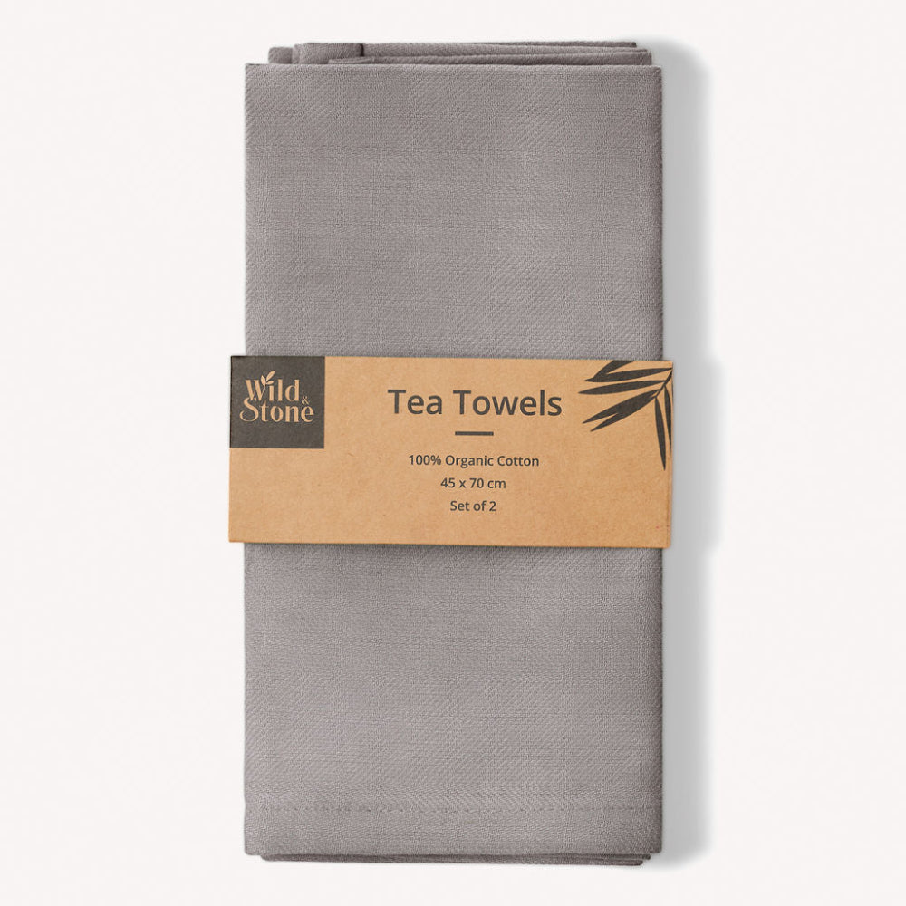Folded grey tea towels with a 'Wild & Stone' label on a white background