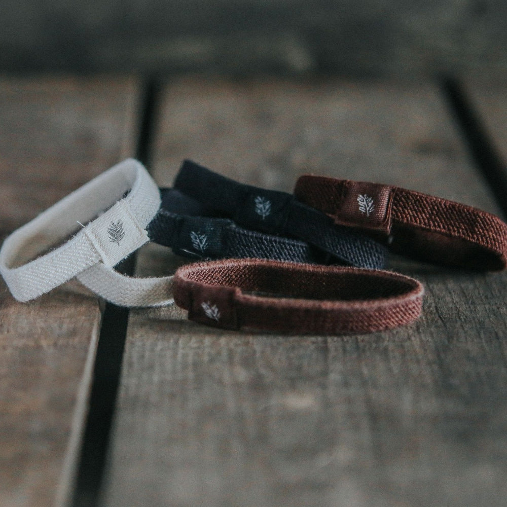 Five plastic free hair ties white, black, and brown on a wooden surface.