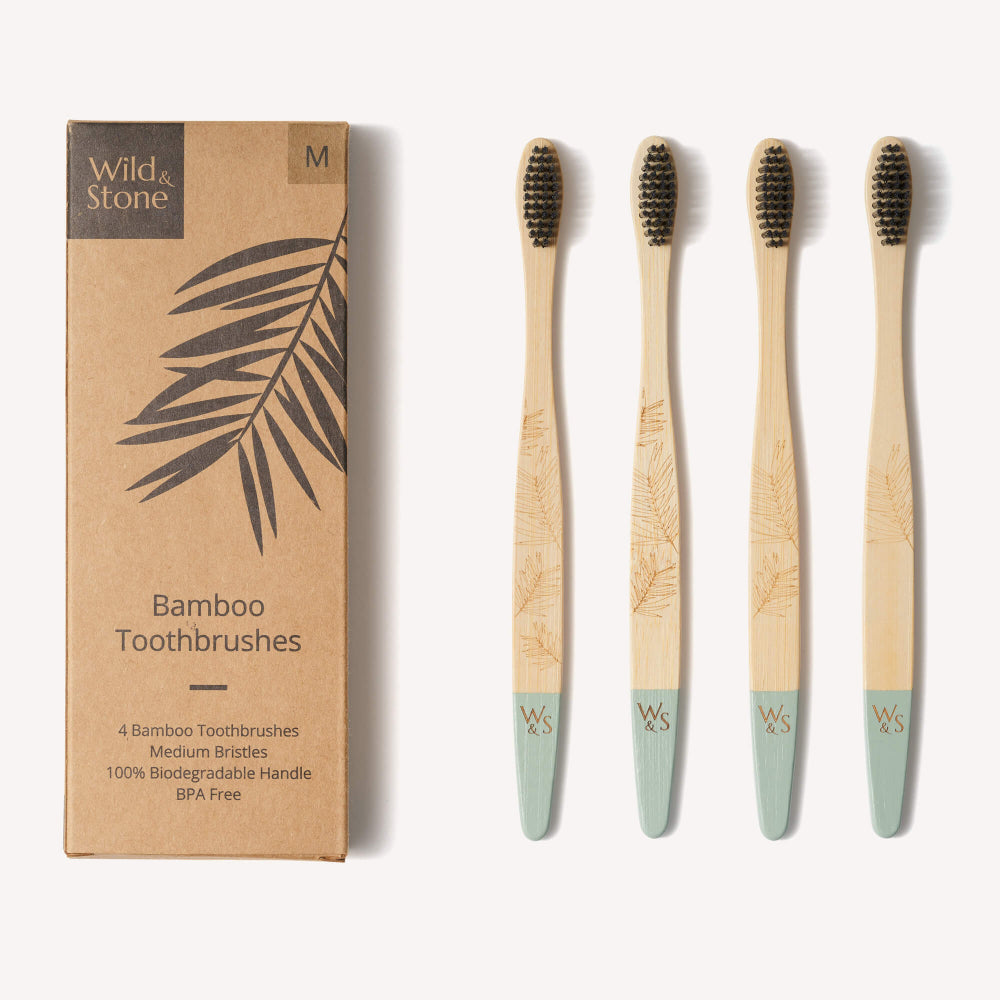 Set of four bamboo toothbrushes with a cardboard box labeled 'Wild & Stone' on a white background.