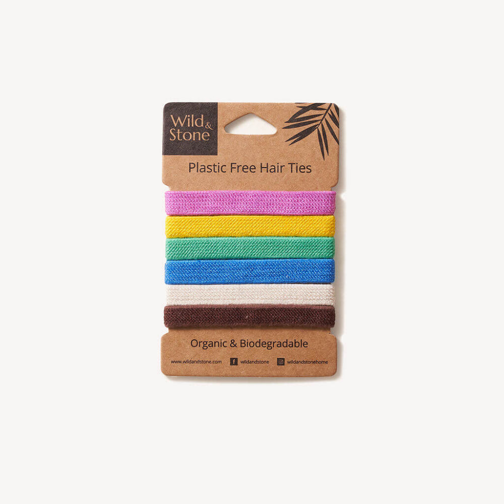 Set of colourful plastic-free hair ties on a cardboard packaging with 'Wild & Stone' branding.