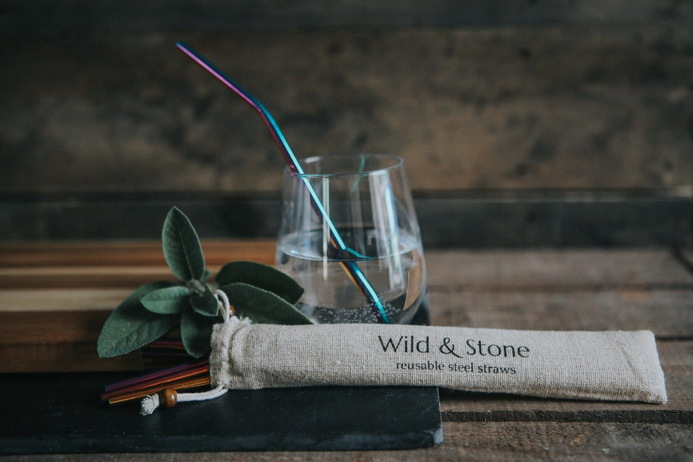 Reusable steel straws with a carrying case labelled 'Wild & Stone' on a wooden surface.