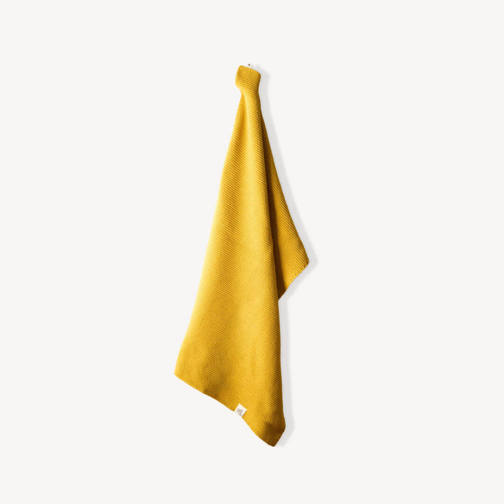 Yellow organic hand towel hanging on a white background